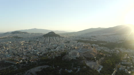 Revealing-drone-aerial-shot-of-Acropolis,-and-city-of-Athens-at-sunrise,-early-morning,-Greece