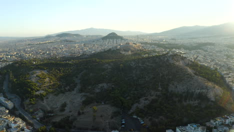 Drone-aerial-shot-flying-over-Athens-park-flying-towards-Acropolis-and-the-centre-of-the-city,-Greece