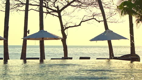 Infinity-Pool-Und-Loungebereich-Mit-Mehreren-Sonnenschirmen-Und-Liegestühlen-Auf-Dem-Sunset-Handheld