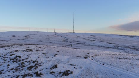 Drone-view-Winter-hill-snowy-rural-broadcast-antenna-signal-towers-on-Lancashire-West-Pennine-moors-slow-pan-right