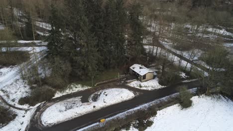 Snowy-rural-hazardous-remote-forest-road-aerial-descent-to-snow-covered-woodland
