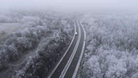 Cars-Traveling-on-Two-Lane-Freeway-Road-in-Wintry-Landscape-in-Sweden,-Aerial