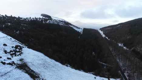 Snowy-cold-Welsh-woodland-Moel-Famau-winter-landscape-aerial-descending-view
