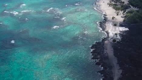 Drone-aerial-black-sand-beach-pan-down-blue-water
