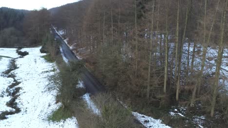 Snowy-Welsh-woodland-Moel-Famau-winter-landscape-aerial-view-rising-reveal-of-road