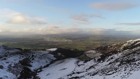 Moel-Famau-Welsh-snowy-mountain-valley-aerial-view-cold-agricultural-rural-winter-landscape-dolly-left