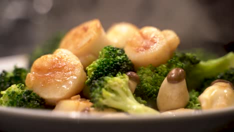 Close-up-shot-of-delicious-hot-freshly-cooked-scallop,-broccoli-and-mushroom-steaming-on-plate