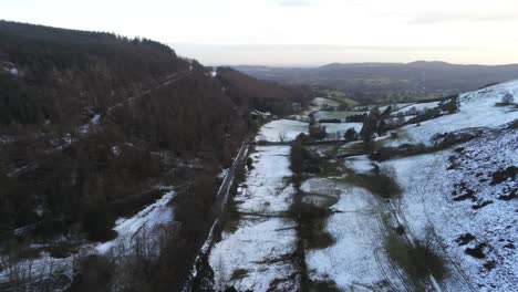 Snowy-rural-Welsh-woodland-Moel-Famau-winter-landscape-aerial-view-dolly-right