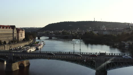 Traffic-on-a-bridge-over-Vltava-river,-Prague,-Czechia,-city-skyline