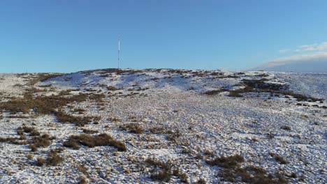 Drone-view-Winter-hill-snowy-rural-broadcast-antenna-signal-towers-on-Lancashire-West-Pennine-moors-high-to-low