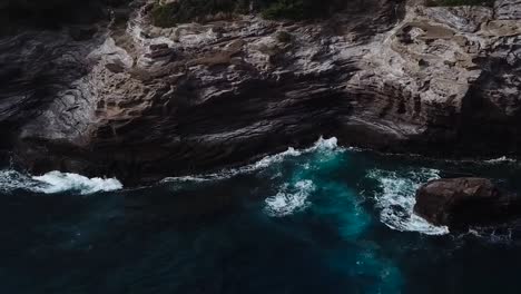 Drone-aerial-pan-right-beach-front-cliff-side-Hawaii