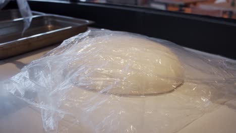 Chef-cover-the-pizza-dough-for-storage-on-kitchen-table-in-the-restaurant