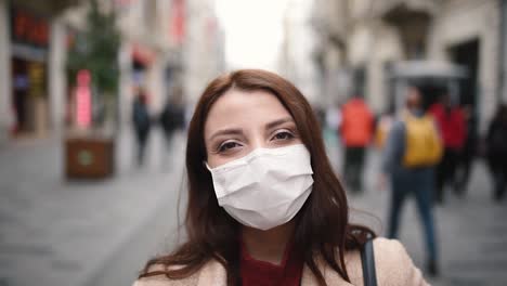 Beautiful-girl-wearing-protective-medical-mask-and-fashionable-clothes-smiles-at-street