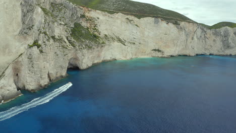Aerial-drone-shot-of-fast-moving-boat-on-a-boat-your-near-shipwreck-beach-in-Zakynthos,-Greece