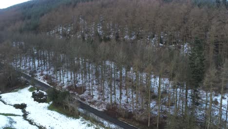 Snowy-Welsh-woodland-Moel-Famau-winter-landscape-aerial-road-follow-view