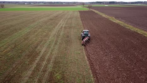 Drone-shot-of-following-a-tractor-plowing-fields-to-prepare-for-sowing
