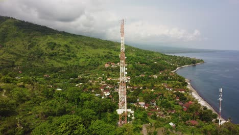 5g-telecom-tower-aerial-drone-rotate-around-pylon-with-ocean-view-and-green-wild-nature-hill-mountain