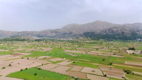 Beautiful-parallax-aerial-shot-of-agriculture-fields-at-Lasithi-Plateau,-Crete