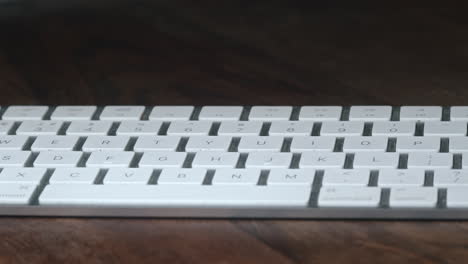 Weiße-Tastatur-Auf-Holztisch-Im-Dunklen-Raum,-Langsame-Parallaxe