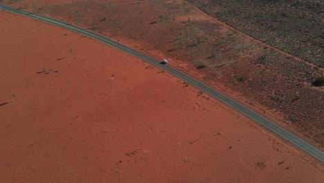árido-Desierto-Rojo-Con-Un-Parque-De-Vehículos-Blanco-En-Una-Carretera-Asfaltada-Durante-El-Verano-En-El-Territorio-Del-Norte,-Australia