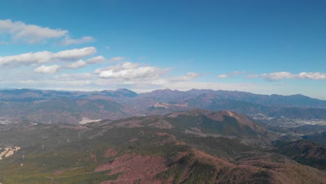 High-above-aerial-drone-over-wide-rolling-mountain-landscape-on-clear-day