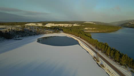Snow-Covered-Lake,-Road-Surrounded-by-a-Lake-on-Both-Sides,-Aerial