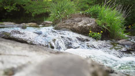 Small-fast-streaming-stream-on-a-small-waterfall-splashing-drops-in-Loch-Lomond,-Scotland