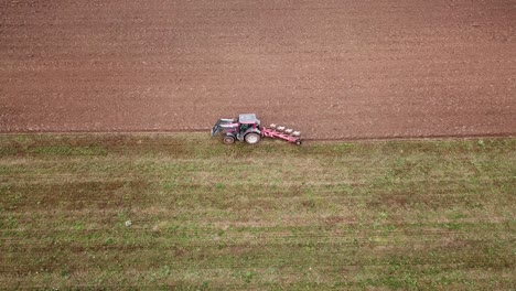 Close-aerial-tracking-shot-of-a-tractor-plowing-a-farmer's-field