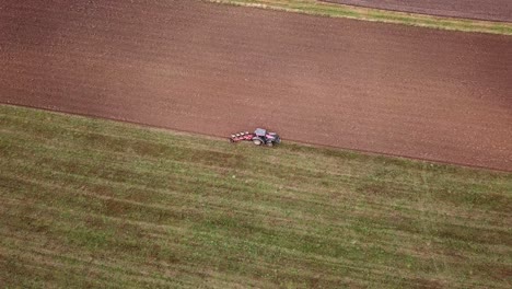 Ein-Traktor-In-Smiltene,-Lettland,-Der-Ein-Großes-Bauernfeld-Pflügt,-Extrem-Weites-Luftbild