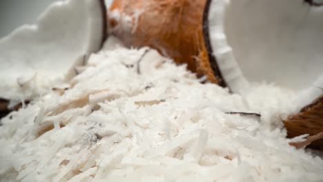 Coconuts-and-shredded-coconut-flakes-close-up-falling-into-tower-ingredient-pull-away-4k-food-product-video
