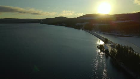 Sunset,-Flying-Along-the-Bridge-at-Sea-Towards-the-Forest,-Aerial