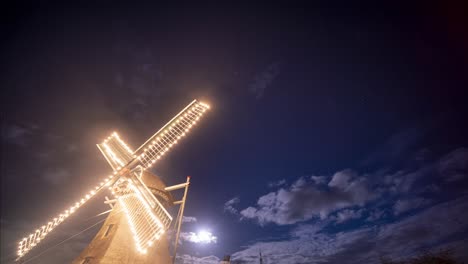 Windmill-Illuminated-In-Lights-Under-A-full-moon-Evening-In-Ameland,-Netherlands---Low-Angle-night-Shot