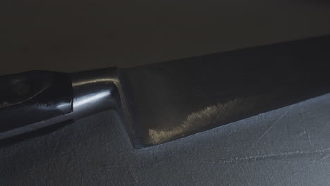 Dramatic-close-up-of-knife-edge-on-stone-surface,-slow-motion