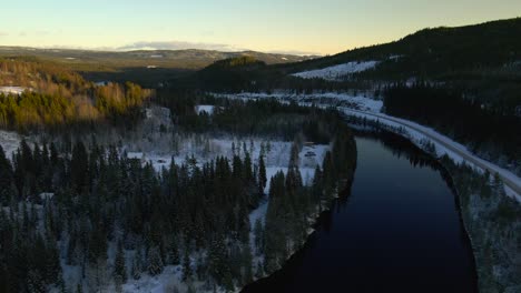 Flying-Over-Curved-River-in-Winter-Landscape-With-Vast-Forest,-Aerial