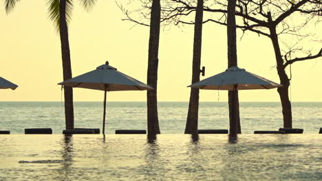 Meerblick-Resort-Mit-Infinity-Pool-Und-Sonnenschirmen-Bei-Sonnenuntergang