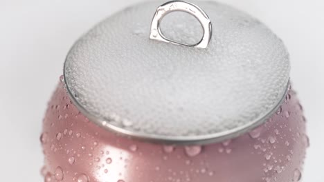Shaken-up-cold-pink-soda-can-opened-slow-motion-bursting-with-bubbles-filling-the-lid