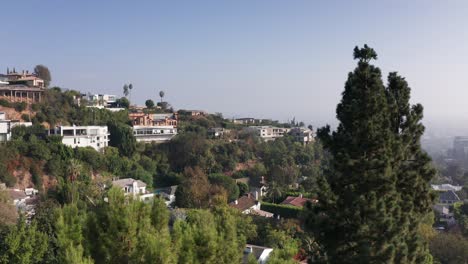 Aerial-shot-of-Beverly-Hills-mansions-on-hillside-with-haze-and-smoky-air-clouding-the-valley-in-the-background