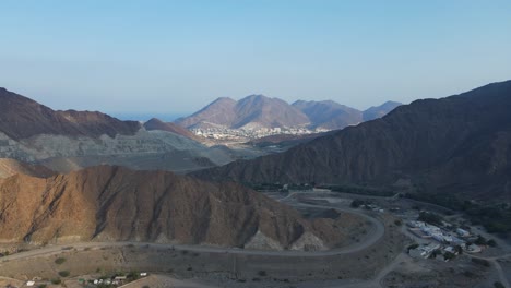 Montañas-De-Los-Emiratos-árabes-Unidos:-Vista-Superior-Del-Pueblo-Y-Las-Montañas-De-Khorfakkan,-Una-Ciudad-Tradicional-Del-Norte-Entre-Las-Colinas