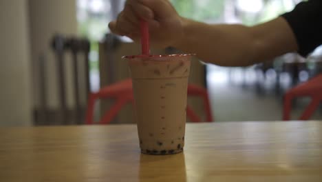 Poking-through-plastic-cup-of-bubble-tea-cup-with-a-plastic-straw