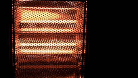 Slowmotion-cinematic-shot-of-turning-on-electric-halogen-heater-in-the-dark-with-copyspace