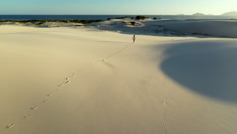 Drone-shot-chasing-a-man-walking-alone-on-sand-dunes