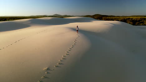 Drone-shot-slow-rising-of-man-walking-alone-on-sand-dunes
