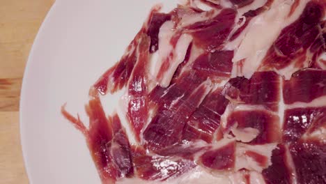 Gourmet-Spanish-Jamon-Iberico-Rotating-on-White-Plate-with-Copy-Space-on-Left