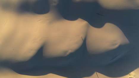 Cinematic-rising-drone-shot-of-man-walking-on-sand-dunes