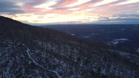 Drone-footage-of-a-forested-mountain-covered-in-light-snow-during-winter-at-dusk-in-the-Appalachian-mountains