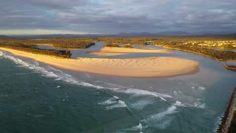 Wide-rising-drone-shot-of-Foster-beach,-the-Nambucca-River-and-ocean-at-Nambucca-Heads-New-South-Wales-Australia