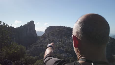 Man-pointing-to-Salto-de-Cabrero-Mountain-Rock-Formation-in-Grazalema,-Spain,-Slow-Motion