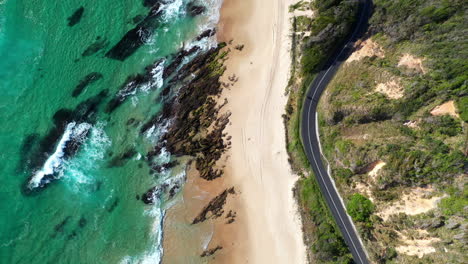 Rising-drone-shot-of-Shelly-Beach-and-the-Wellington-Rocks-with-coastal-highway-and-ocean-waves-at-Nambucca-Heads-New-South-Wales-Australia