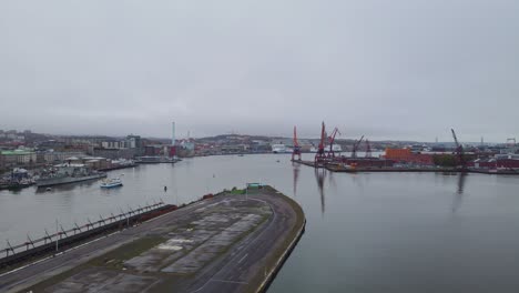 Drone-Flying-Above-Street-Parking-Surrounded-By-Quay-In-Gothenburg,-Sweden-With-View-Of-Cranes-On-Industrial-Port,-aerial