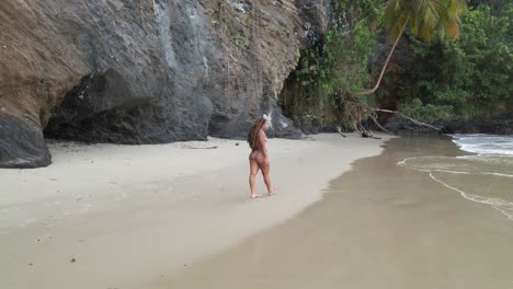 Drone-view-of-a-girl-in-bikini-walking-on-the-sand